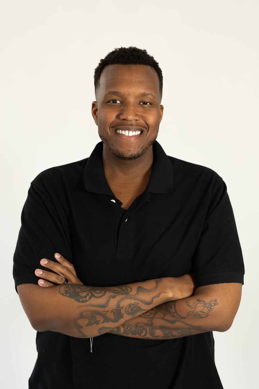 Dexter Brocks, founder of Charming AI Consulting, smiling with arms crossed in a black polo against a soft studio backdrop.